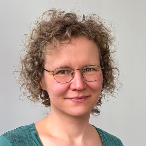 SK_glanzhelden_02 Porträt einer lächelnden Frau mit blonden Haaren, die einen grünen Pullover und eine Brille trägt