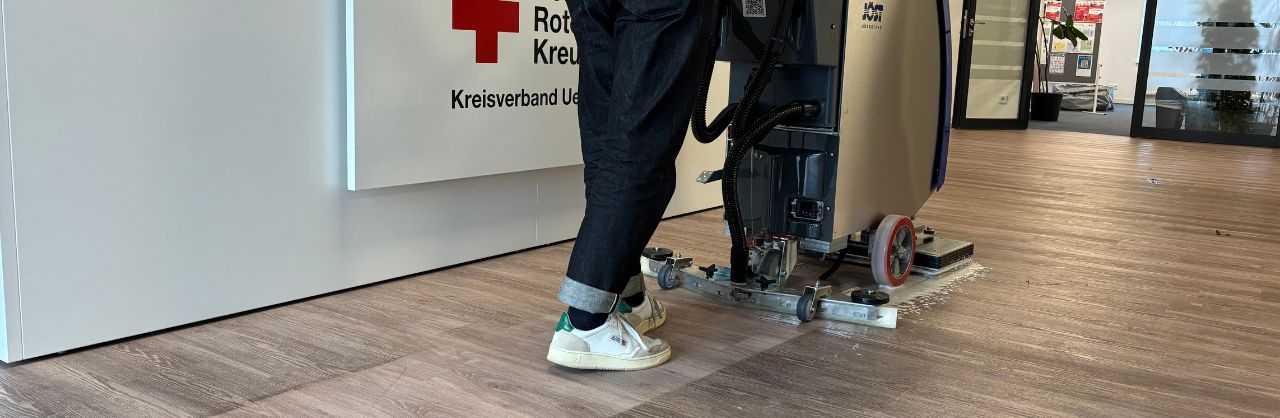 Reinigungskraft mit Reinigungsmaschine beim Säubern eines Bürogebäudes im Deutschen Roten Kreuz Uelzen